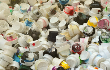A large number of caps from cans of aerosol paint for graffiti. Smeared with colored paint nozzles...