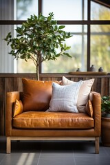 A leather chair with a gray and white pillow in a bright room with a tree
