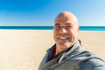  Happy man takes a selfie on the beach on a winter day