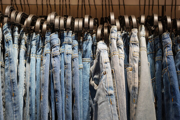 Many blue jeans hang on a rack. shopping, selling