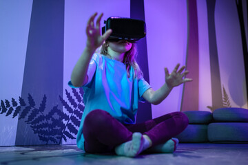 Female child using new technologies, having fun wearing virtual reality goggles in the VR room of...