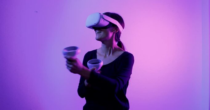 Young woman with virtual reality headset playing a game with hand controllers