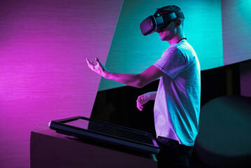 Young man in VR glasses standing at a touch screen table, making hand gestures in the air. Virtual...