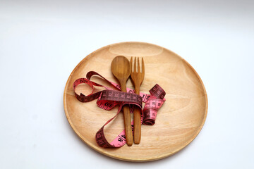 wooden spoon and fork and measuring tape on a wooden plate with vegetables arranged into the word...