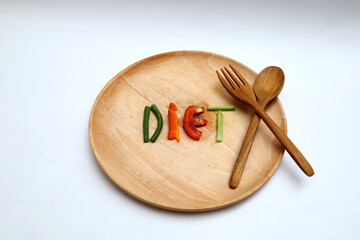 the word diet on a wooden plate made of sliced ​​vegetables such as tomatoes, long beans,...