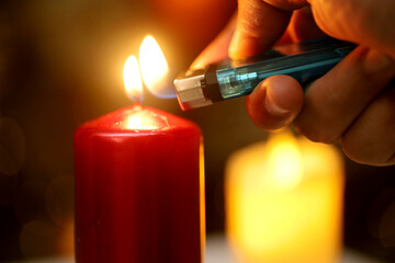 hand lighting a candle with a lighter on blur and bokeh background.