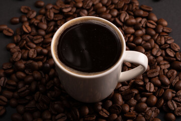 In this close-up photo, cup of espresso, by textured coffee beans, becomes a visual symphony of energy and caffeine. The rich texture of the beans invites contemplation, making this image a perfect 