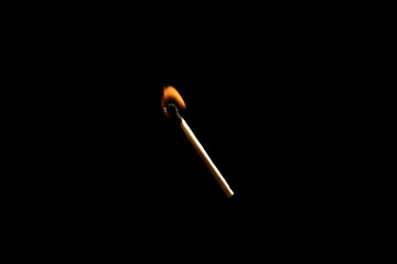 Lit falling match on a black background.