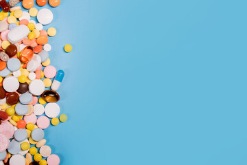 Colorful pills and capsules on blue background. Minimal medical concept. Copy space