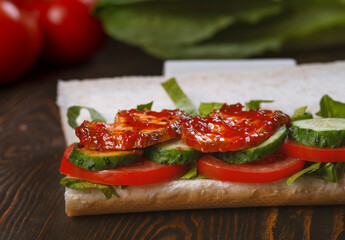 Sandwich with cucumber, tomato and basil on a wooden background