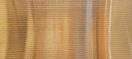 gold glass sheet wall or corrugated wall pattern texture use as background. frosted wave glass in horizontal line pattern in the translucent and polished effect.