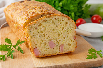Zucchini bread with cheese, ham and fresh herbs on a wooden board on a gray background. Healthy food.