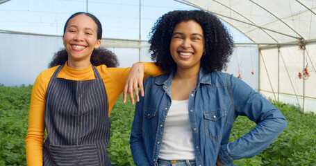 Portrait of two female farmers standing in greenhouse field smiling and laughing