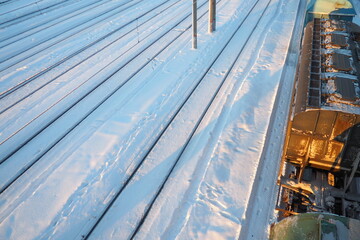 Railway station. Passenger freight trains on rails. Winter short polar day. Snow and snowdrifts