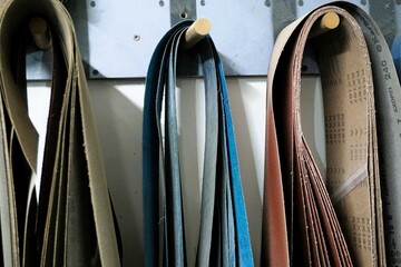 Bunte Schleifpapierbänder hängen an Wand in Werkstatt 