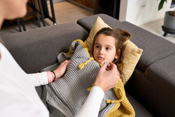 A child's small hands eagerly receiving a probiotic tablet from the gentle hands of their mother. A...