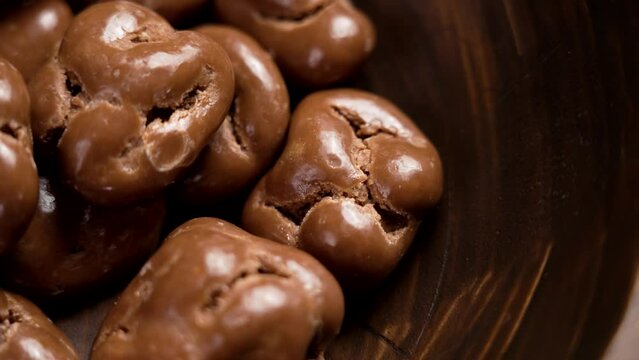 Milk chocolate glazed walnuts in brown wooden bowl close up. Rotation