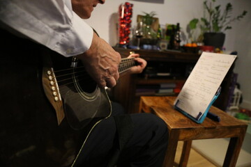 man playing guitar from sheet music at home