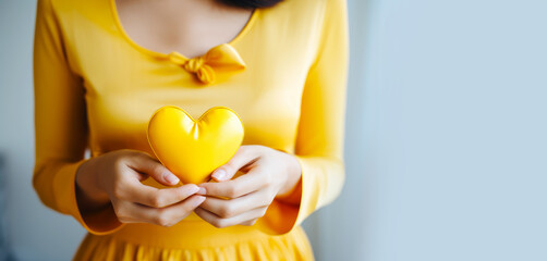 A woman hold yellow heart for endometriosis awareness campaign, suicide prevention , Childhood cancer.
