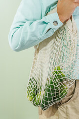 fresh cucumbers in a shopping bag that hangs on a girl's shoulder