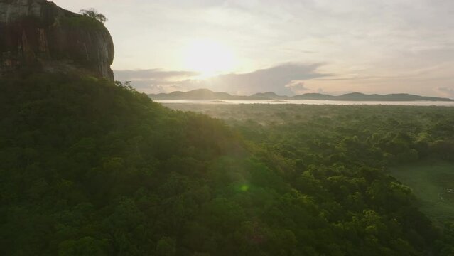 Beautiful aerial landscape shot of tropical forest against sunrise. Backwards revealing rock wall. Sigiriya, Sri Lanka