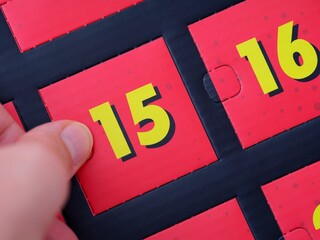 A woman hand opening a door with number 15 on an advent calendar.
