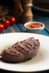 Roasted steak ,cherry tomatoes, salt and pepper on blue  wooden table.