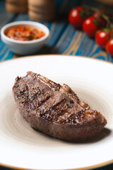 Grilled steak ,cherry tomatoes salt and pepper on wooden table.