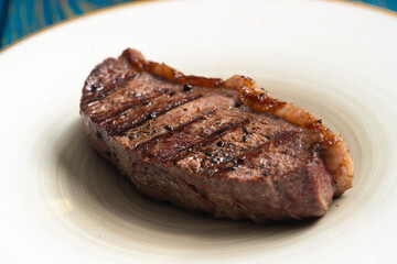 Fresh grilled meat.steaks with spices in white plate on blue wooden background