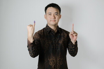 Asian man wearing Indonesian traditional Batik cloth is showing his little finger with purple ink...