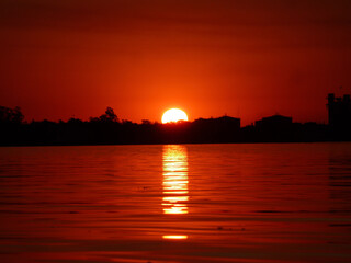 Naklejka premium El sol de esconde detrás de los arboles costeros del río Coronda, perteneciente al delta del uno de los ríos mas grandes de Sudamérica como lo es el río Paraná.