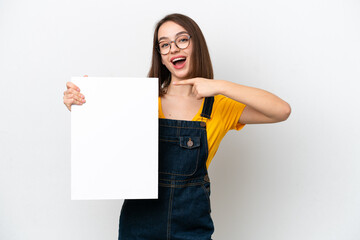Young Ukrainian woman isolated on white background holding an empty placard with happy expression and pointing it