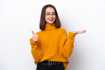 Young Ukrainian woman isolated on white background holding copyspace imaginary on the palm to insert an ad and with thumbs up