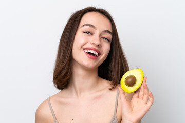 Young Ukrainian woman isolated on white background holding an avocado while smiling. Close up portrait