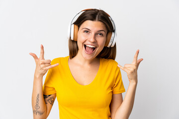 Young slovak woman isolated on white background listening music making rock gesture