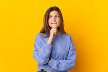 Young Slovak woman isolated on yellow background having doubts and thinking