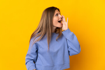Young Slovak woman isolated on yellow background shouting with mouth wide open to the side