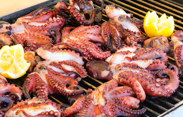 octopus with tentacles cooked on the metal grill in the seafood restaurant with lemon