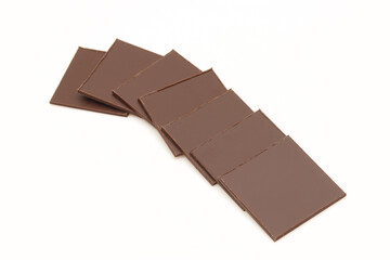 Stack of thin square pieces of chocolate isolated on white background.