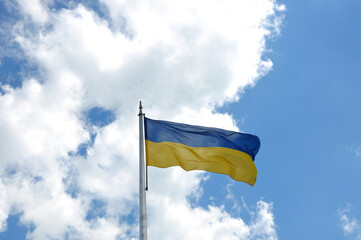 Flag of Ukraine against the blue sky. White clouds on the blue sky.