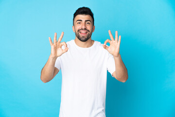 Naklejka premium Caucasian man over isolated blue background showing ok sign with two hands