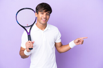 Handsome young tennis player man isolated on ocher background pointing finger to the side
