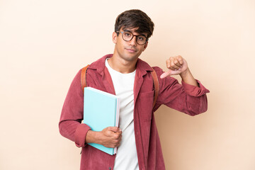 Young student caucasian man isolated on ocher background showing thumb down with negative expression
