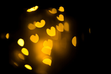 blurred bokeh withe hearts in golden, yellow colors on black background 14