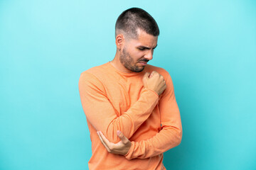 Young caucasian man isolated on blue background with pain in elbow