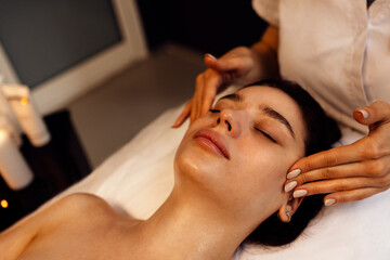 Close up portrait of a young beautiful woman getting facial massage