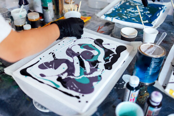 Master class on an Acrylic Fluid Pouring. Young women paint with liquid acrylic in an art workshop