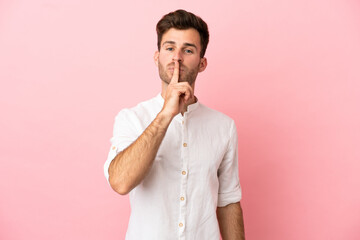 Young caucasian handsome man isolated on pink background showing a sign of silence gesture putting...