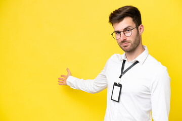 Young caucasian with ID card isolated on yellow background extending hands to the side for inviting...