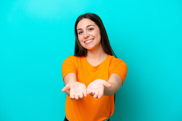 Young caucasian woman isolated on blue background holding copyspace imaginary on the palm to insert an ad © luismolinero